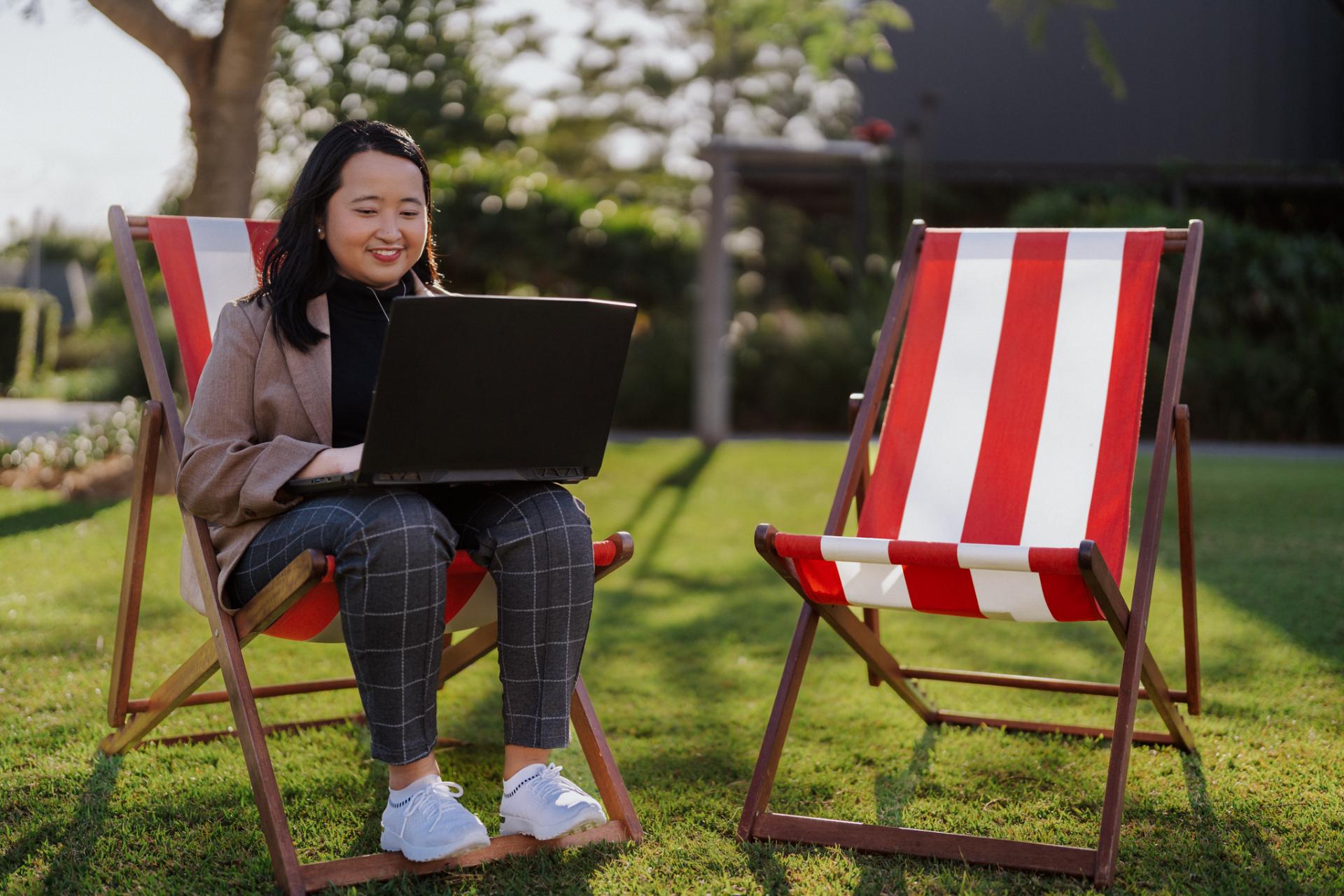 Female student sitting on a striped deck chair with a laptop at ACU Brisbane. 