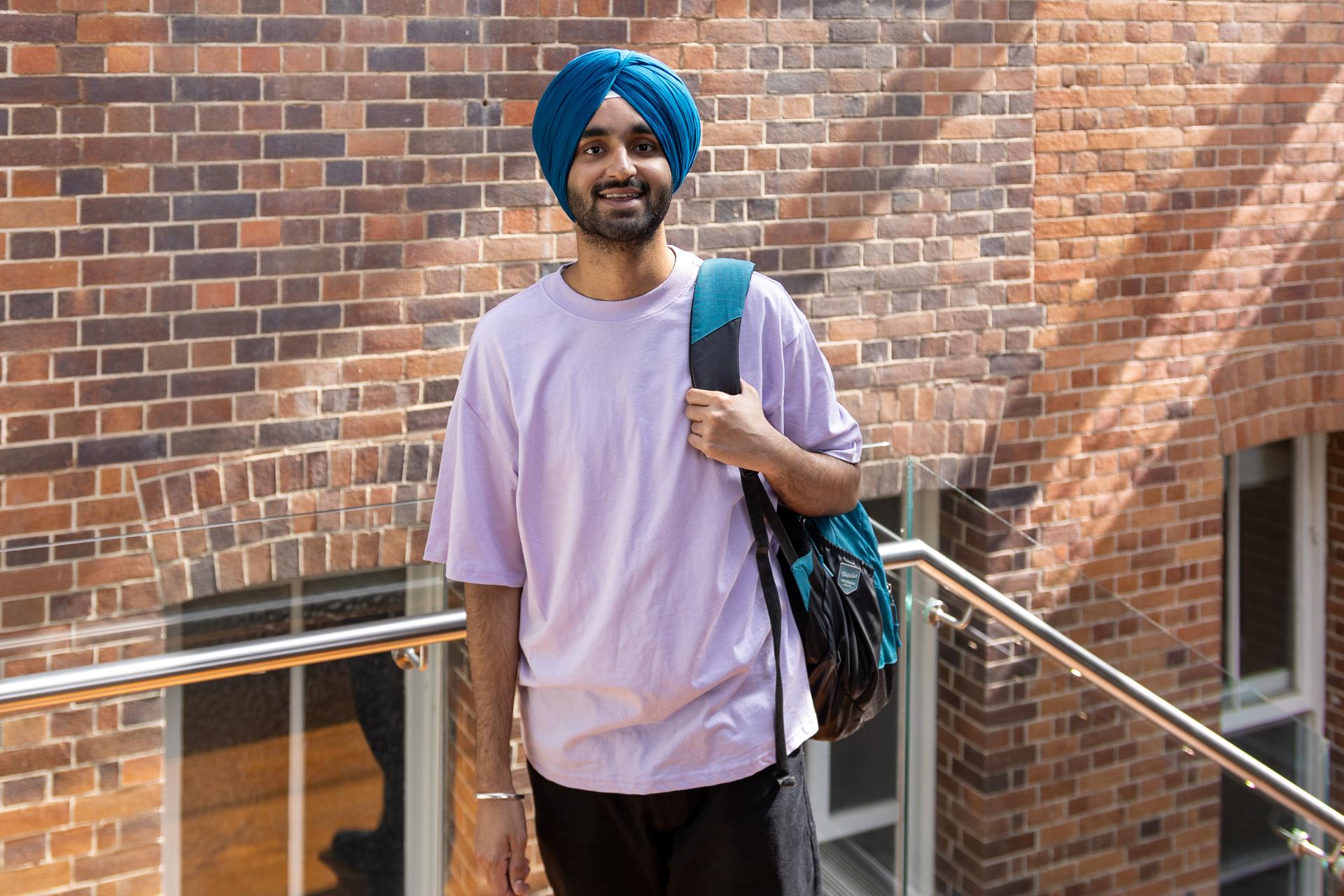 Student from India with a backpack standing on campus at UQ Brisbane. 